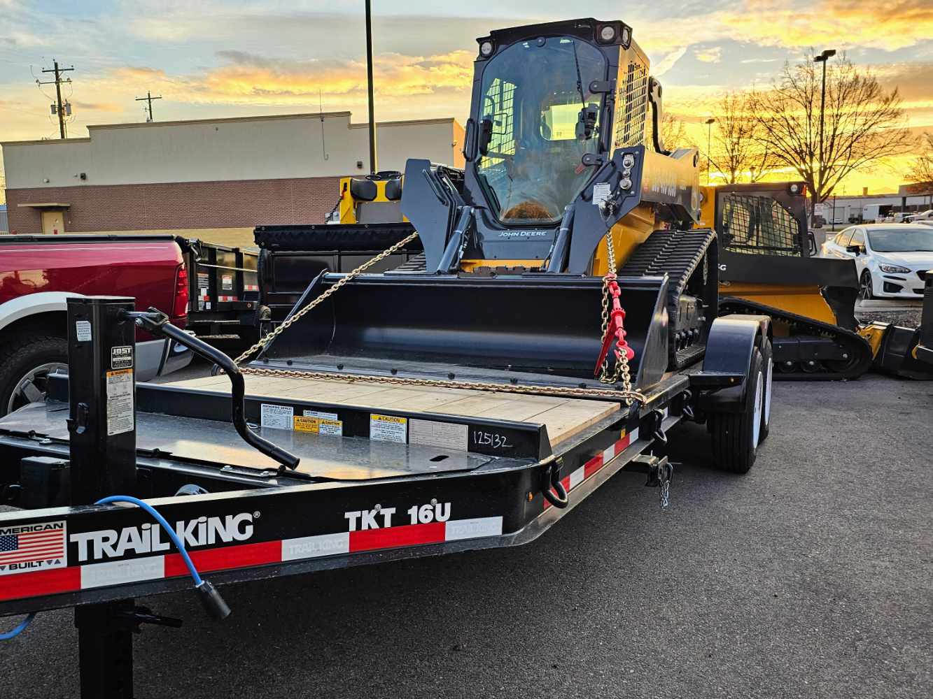 black-flatbed-trailer-loaded flatbed trailer with skid steer loaded on it